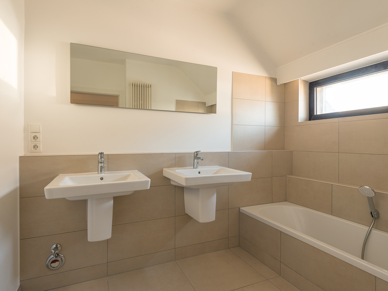 Bathroom interior in a colocation Luxembourg. It includes two sinks, a bathtub, and a mirror