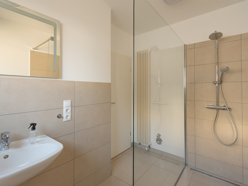 Bathroom interior in a colocation Luxembourg. It includes a sink, a shower, and a mirror