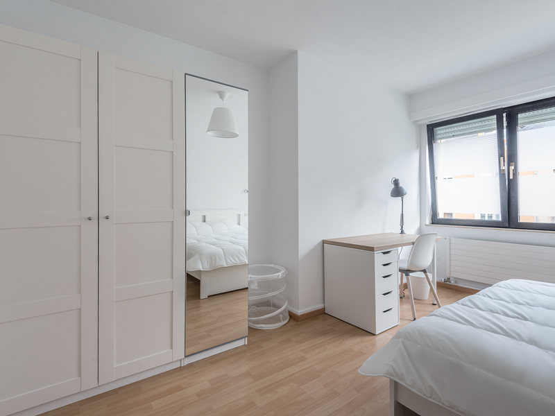 Coliving in Luxembourg city - furnished room with a double bed, bedside table, desk, chair, wardrobe.