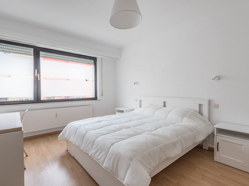 Coliving in Luxembourg city - furnished room with a double bed, bedside table, desk, chair, wardrobe.