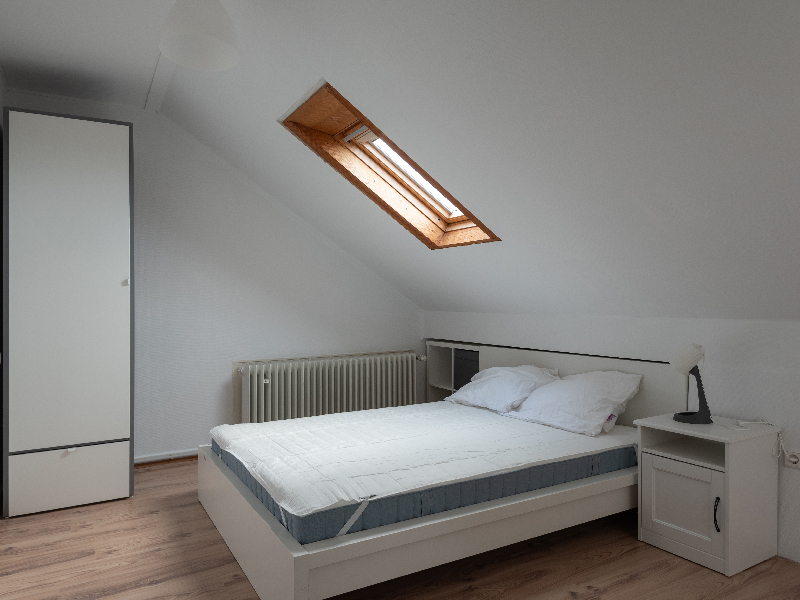 Furnished room for rent in Luxembourg. The room includes a double bed, bedside table, wardrobe, desk and mirror.