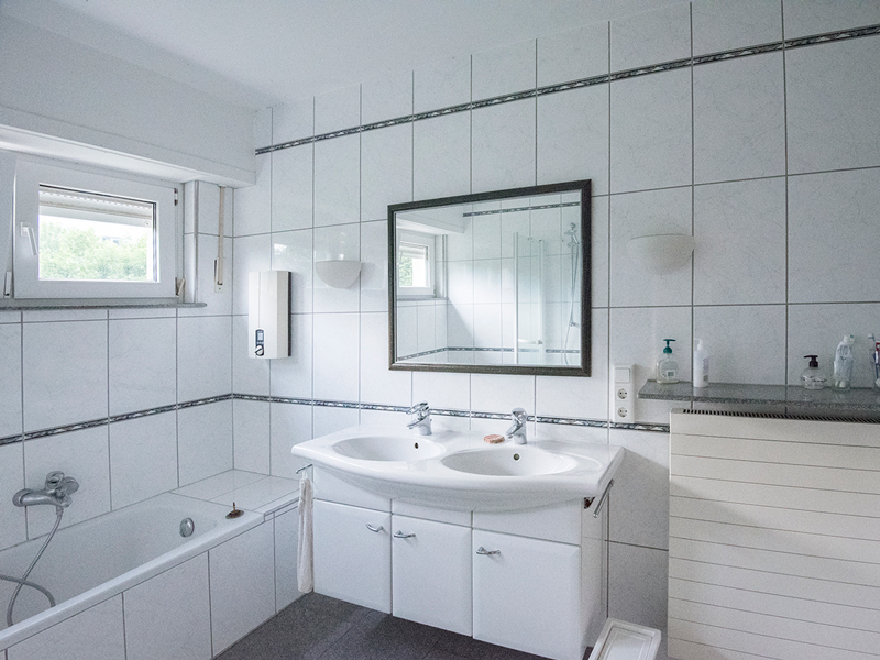Luxembourg shared house bathroom interior with a bathtub, two sinks and a mirror