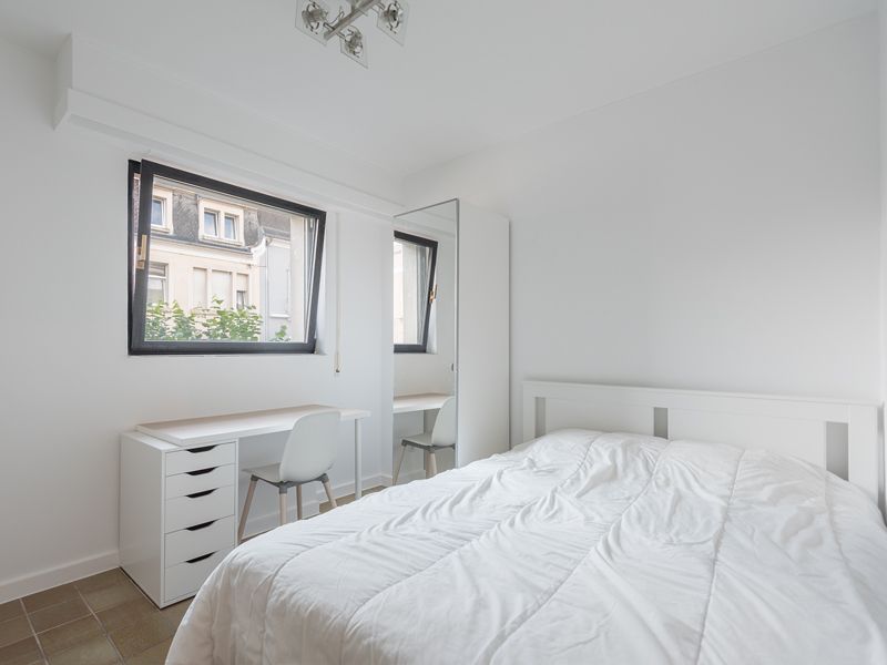Furnished room for rent - Colocation Luxembourg. It includes a double bed, a wardrobe, a desk, and a chair.