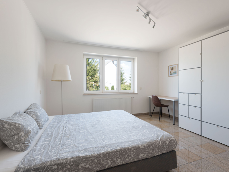 Furnished Room for Rent in Luxembourg. The room includes a double bed, bedside table, desk, chair, wardrobe, shelf.