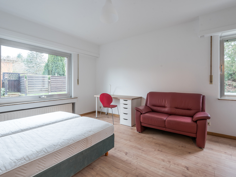Furnished Room for Rent in Luxembourg. The room includes a double bed, a bedside table, a wardrobe, a sofa, a desk and a chair.