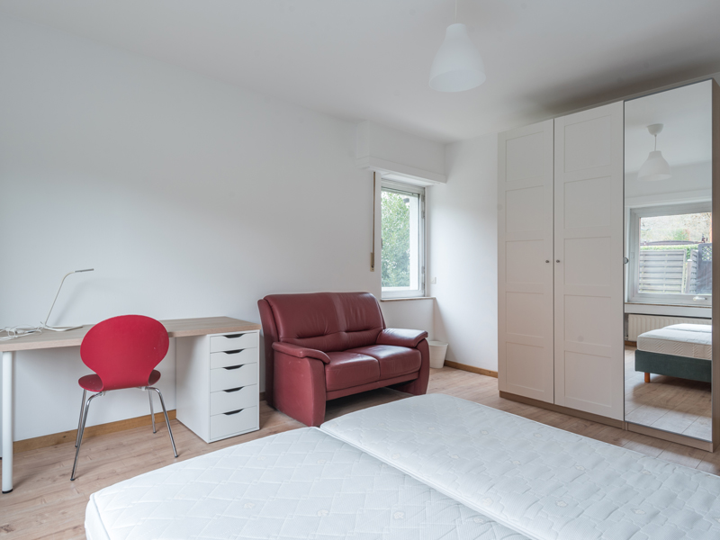 Furnished Room for Rent in Luxembourg. The room includes a double bed, a bedside table, a wardrobe, a sofa, a desk and a chair.