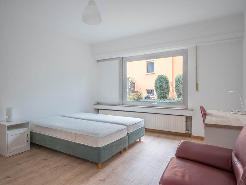 Furnished Room for Rent in Luxembourg. The room includes a double bed, a bedside table, a wardrobe, a sofa, a desk and a chair.