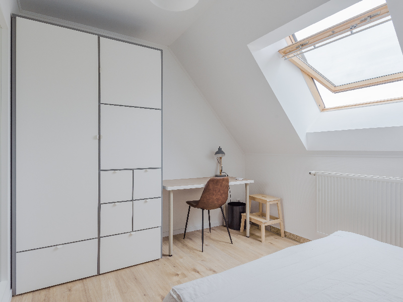 Furnished room for rent in Luxembourg. The room includes a double bed, bedside table, wardrobe, desk, mirror, shelf and a chair.