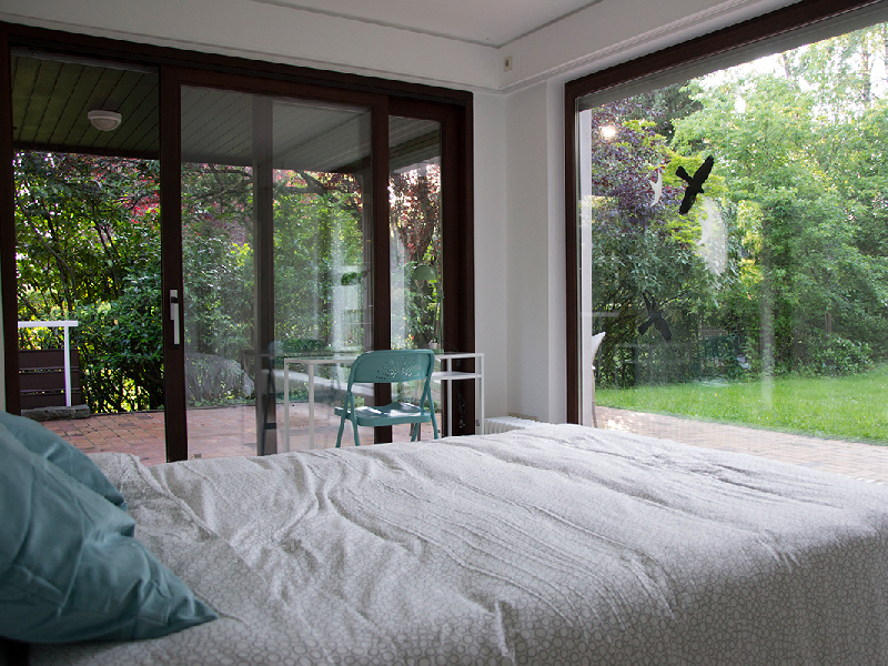 A brightly lit furnished bedroom in a Luxembourg houseshare, featuring a dedicated workspace with a desk and chair.